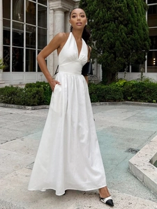 Detail of elegant white halter neck maxi dress with deep V-neckline and pleated waist detail