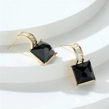 Detailed close-up of golden sea turtle earrings featuring black square-cut faceted zircons