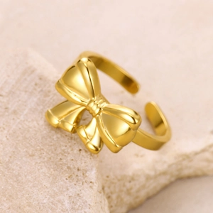 Macro shot of gold bow-shaped open adjustable ring on minimalist stone background