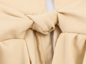 Detailed macro view of beige fabric knot craftsmanship on a long sleeve dress