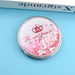 Vue détaillée du miroir pliable rond avec sable mouvant rose et paillettes cœur