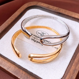 Close-up of gold and silver plated open bangles with droplet overlapping design