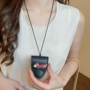 Detail of dachshund pendant on a leather necklace with a red and white striped sweater