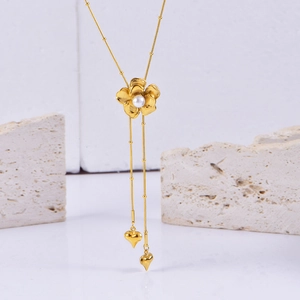 Macro view of golden flower pendant with pearl accents and heart charms on a sleek chain
