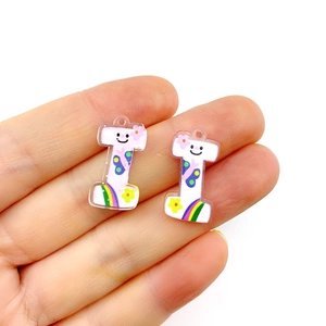 Close-up of small white acrylic charms with colorful rainbow and smiley patterns for DIY