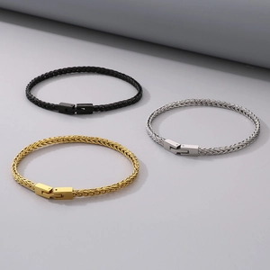 Dettaglio di bracciali a catena intrecciata hip hop nei colori nero, oro e argento lucido
