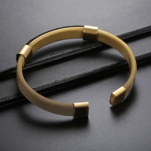 Detail of gold woven stainless steel mesh bracelet with polished metal end caps