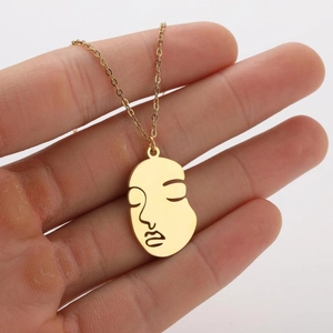 Detail of 18K gold plated necklace featuring an abstract face outline on an oval pendant