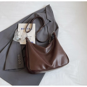 Detailed close-up of dark brown soft leather tote bag with chain strap and chic texture