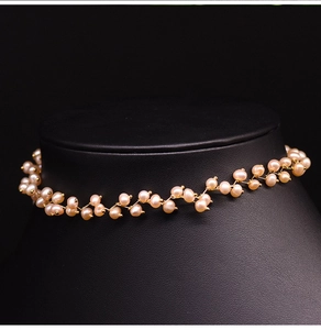 Close-up of pink freshwater pearls in a wavy gold wire choker on black necklace display stand