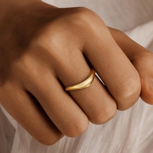 Close-up of elegant gold layered ring with curved lines worn on a model hand