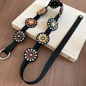 Detail of vintage leather belt with colorful flower appliqués and silver metal rivets