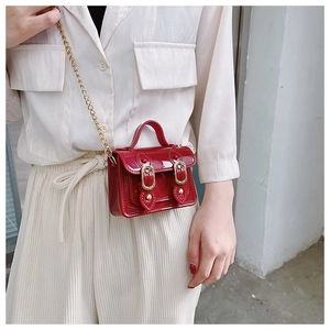 Detail of red mini jelly bag with gold chain strap worn by model on waist