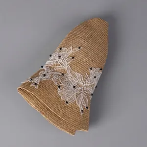 Foldable women's straw sun hat with white lace floral details and wide brim for beach travel