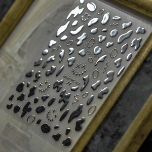 Detail of silver laser nail stickers with abstract water drops and ring patterns