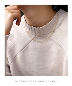 Close-up of a gold-plated necklace with zircon beads worn on a neck, elegant style
