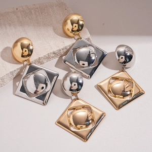 Modern geometric gold and silver tiered square earrings on aesthetic stone backdrop