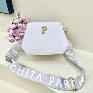 Detail view of white PU leather tote with hexagonal flap and gold hardware accents
