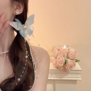 Detail of blue butterfly hair clip with long pearl tassels on wavy hair with roses