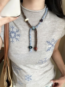 Detail of bohemian handmade woven necklace with colorful beads on a grey sweater