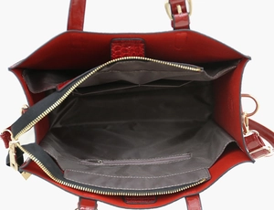 Draufsicht auf das Innenfutter der roten Handtasche mit drei Fächern und Goldreißverschluss