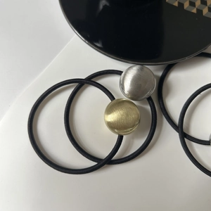 Detail of high-elastic black hair ties with brushed gold and silver metal alloy balls