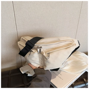 Detail of beige nylon crossbody bag with multi-layer zippers and adjustable wide strap