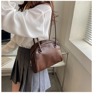 Brown leather shoulder bag styled on a model in a minimalist office setting