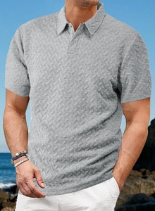 Détail d'un polo gris pour homme en tissu texturé à chevrons sur fond de mer