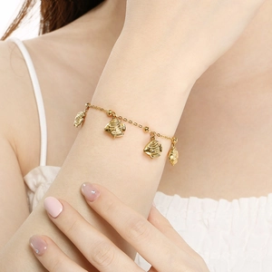 Gold plated stainless steel bracelet with tropical fish charms worn on a wrist