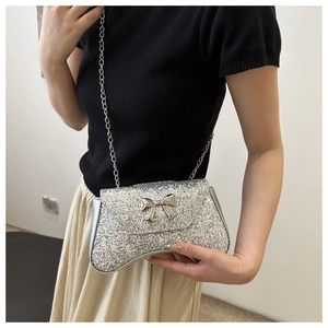 Silver sequin shoulder bag featuring a metallic bow detail and fine chain strap