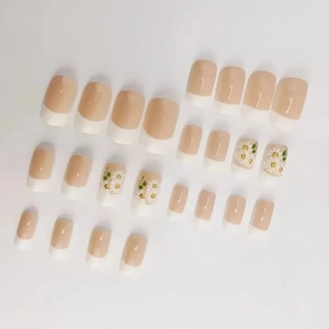 French press-on nails set with elegant white daisies and green leaves on nude pink base