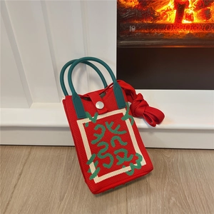 Detail of red knit mini crossbody bag with green ring handles and silver metal button