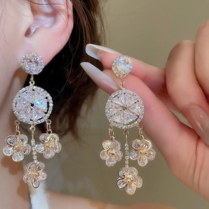 Detailed view of silver flower tassel earrings with zircons shown on ear for scale