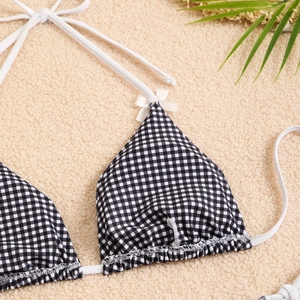 Close-up of black and white gingham bikini top with delicate white bows and tie straps