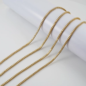 Golden titanium stainless steel box chain necklaces displayed on a white platform