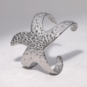 Detailed close-up of a silver starfish cuff bracelet with realistic textured grain details