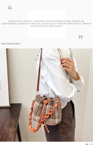 Detail of plaid wool bucket bag with orange woven handle and leather drawstring closure