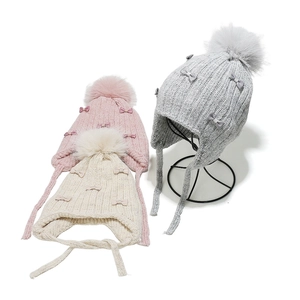 Girl's knit hat with pom-pom and bow accents, ear flaps in pink, beige and gray