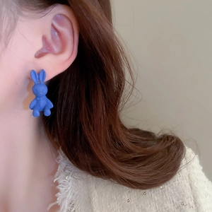 Close-up of model wearing Klein blue rabbit ear studs with a soft matte finish