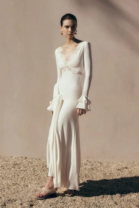 Close-up of elegant V-neck lace patchwork and flared ruffle sleeves on cream dress