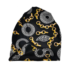 Detailed view of black knitted beanie featuring golden chain and Greek key pattern prints
