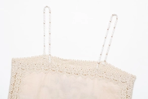 Close-up of beige knit camisole featuring delicate lace trim and braided shoulder straps