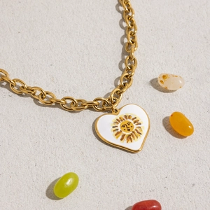 Macro view of gold-plated stainless steel necklace with white enamel sun heart pendant