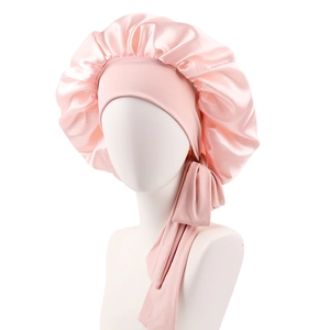Detailed view of the pink satin sleep cap with wide adjustable ribbons on a mannequin