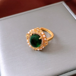 Detailed close-up of a 24k gold plated ring with green oval stone and pearl accents