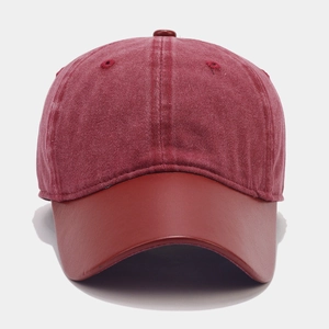 Detail of burgundy washed cotton baseball cap with smooth contrast leather brim and texture