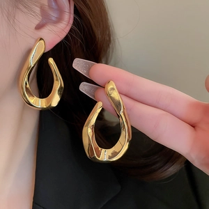 Detailed view of gold twisted oval earrings showing size and model wear effect