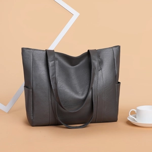 Grey large capacity leather tote bag with dual shoulder straps on a minimalist background