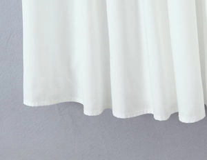 Détail de l'ourlet d'une robe blanche en tissu drapé doux avec des coutures fines